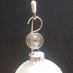 May include: A white glass ornament with a silver metal top and a silver wire spiral ornament attached to the top.