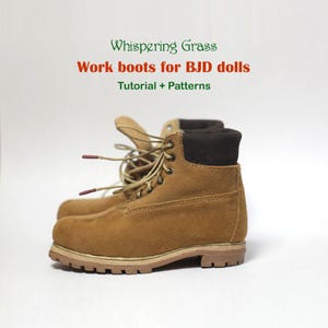 May include: A pair of miniature work boots in a tan suede material, designed for BJD dolls. The boots have brown laces, a brown collar, and a light brown sole. The text "Whispering Grass" and "Work boots for BJD dolls Tutorial + Patterns" is visible.