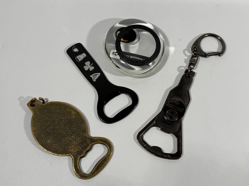 May include: An assortment of bottle openers in various designs. Includes a black bottle opener with a shamrock design, a bronze-colored bottle opener, a bottle opener shaped like a beer bottle, and a silver-colored bottle opener.