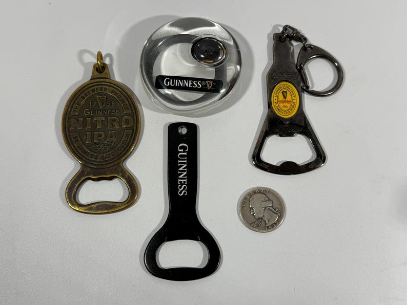 May include: A collection of Guinness-branded bar accessories, including a bottle opener keychain, a round bottle opener, and a black bottle opener. Also includes a brass Nitro IPA bottle opener and a quarter.