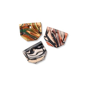 May include: Three small, marbled leather pouches in shades of brown, green, black, and cream. Each pouch has a circular hole near the top and a unique swirling pattern. The pouches are arranged on a white background.