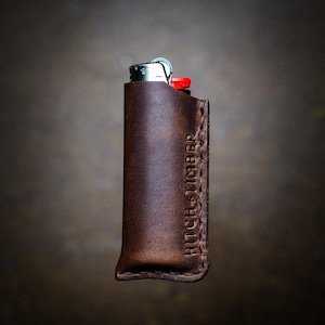 May include: A brown leather lighter case with the text "HITCH MEMBER" embossed on the side.