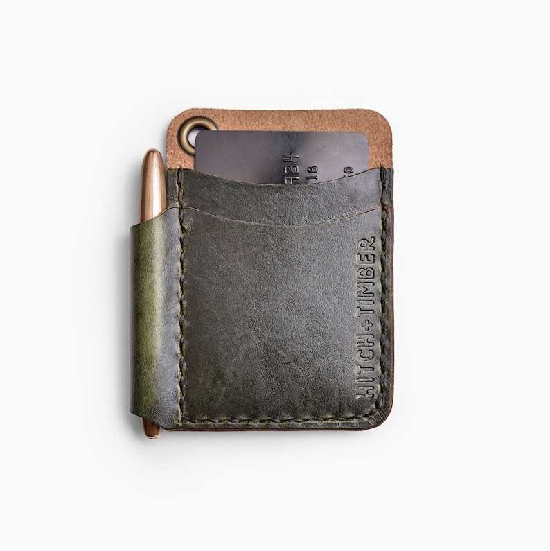 May include: A green leather wallet with a pen holder and a card slot. The wallet has the text "HITCH + TIMBER" embossed on the front.