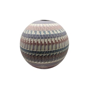 May include: A spherical, handcrafted ceramic vase with a detailed geometric pattern. The vase features a color palette of brown, blue, and cream, with a dark opening at the top. The design includes repeating shapes and lines, creating a textured appearance.