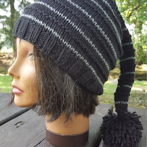 May include: Black and grey striped knit beanie with a long tail and a black pom pom.