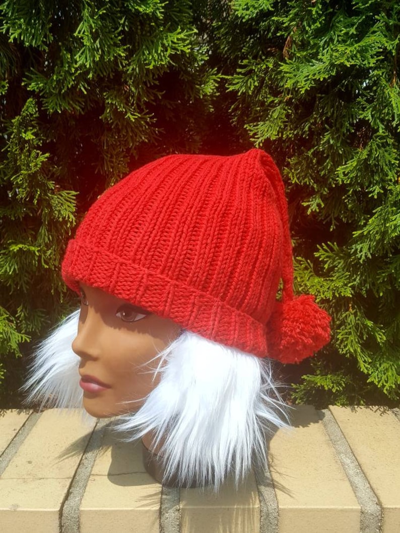 Puede incluir: Gorro de punto rojo con un pomp&oacute;n blanco y orejeras de piel sint&eacute;tica blanca.