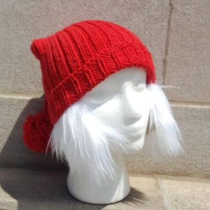 Puede incluir: Un gorro de punto rojo con un pomp&oacute;n blanco en la parte superior y un ribete de piel blanca alrededor del borde. El gorro est&aacute; en una cabeza de maniqu&iacute; blanca.