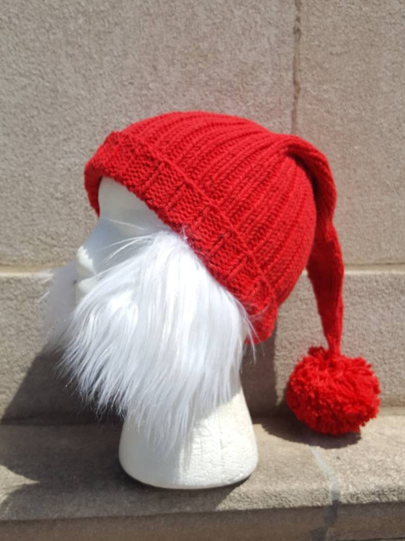 Puede incluir: Un gorro rojo de punto con una larga punta puntiaguda y un pomp&oacute;n en el extremo. El gorro tiene una barba de piel sint&eacute;tica blanca unida a la parte delantera.