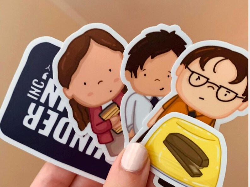 May include: Three cartoon stickers featuring characters from the TV show "The Office". The stickers are on a white background. The first sticker is of a woman with brown hair wearing a red shirt and holding a coffee cup. The second sticker is of a man with brown hair wearing a white shirt and tie. The third sticker is of a man with brown hair wearing an orange shirt and glasses. He is holding a yellow gelatin mold with a brown stapler inside. The text "Dunder Mifflin Inc." is visible on the bottom left corner of the image.