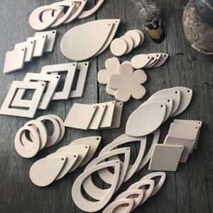 May include: A selection of leather shapes for crafting, including circles, squares, ovals, teardrops, and flowers. The leather is a light beige colour.
