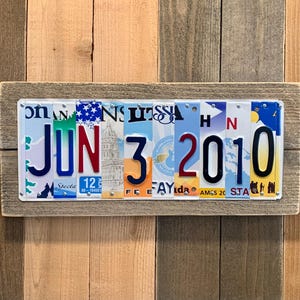 May include: A wooden sign with the date June 3, 2010 spelled out using license plates. The sign is made of reclaimed wood and has a rustic look.