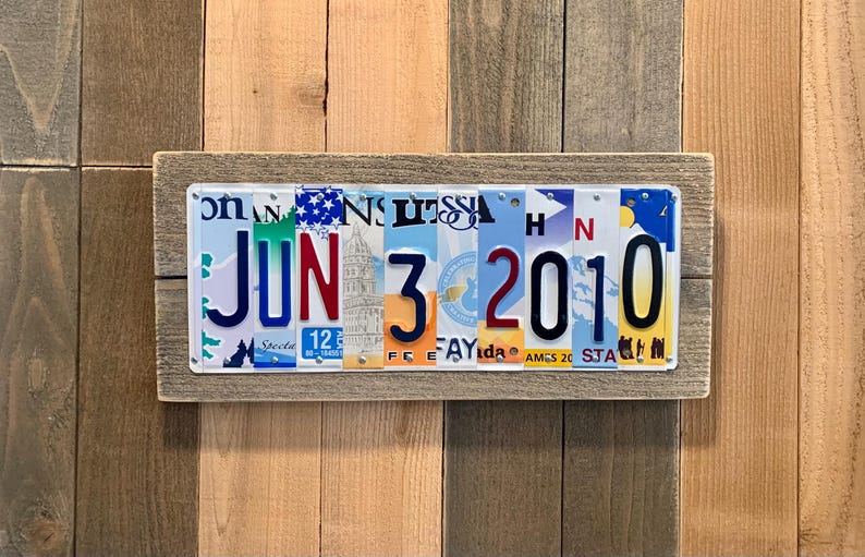 May include: A wooden sign with the date June 3, 2010 spelled out using license plates. The sign is made of reclaimed wood and has a rustic look.