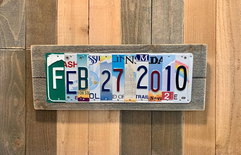 May include: A wooden sign with a date made from license plates. The date is February 27, 2010.