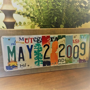 May include: A wooden sign with the date May 22, 2009 spelled out using vintage license plates. The plates are arranged horizontally and feature a variety of colors and designs.