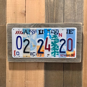 May include: A framed wall decor piece made from repurposed license plates. The license plates are arranged to form the date "022420".