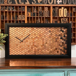 This clock has a gorgeous ombre pattern, which utilizes the patina of both new and old pennies. It simply GLOWS. And as an added bonus, it contains a hidden gem - a wheat penny. How cool is that? 
25.75" x 13.75" black frame