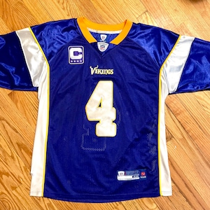 May include: A blue and white football jersey with the number 4 and the word "Vikings" on the front. The jersey has yellow trim and a small logo on the left chest.