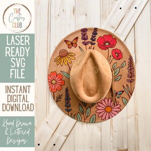 Op de afbeelding: Een bruin cowboyhoed met een bloemenontwerp met rode klaprozen, gele madeliefjes en vlinders. De hoed is een laserklare SVG-bestand voor direct digitale download. De tekst luidt "LASER READY SVG FILE" en "INSTANT DIGITAL DOWNLOAD".