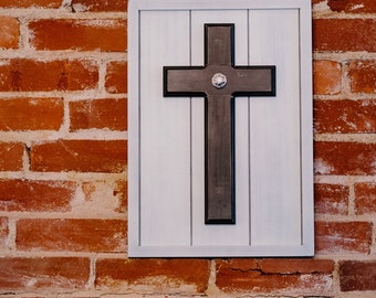 May include: A framed wooden cross with a white background and a black cross with a small silver embellishment in the center.