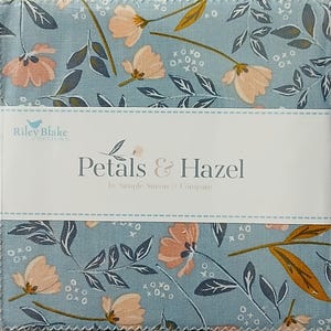 May include: A stack of fabric squares featuring a light blue background with a floral pattern of peach-colored flowers, dark blue leaves, and small white x and o symbols. A white paper band wraps around the center with the text Petals & Hazel.