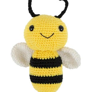 May include: A crocheted bee plush toy with yellow and black stripes, white wings, and black antennae. The bee has a smiling face with black eyes.