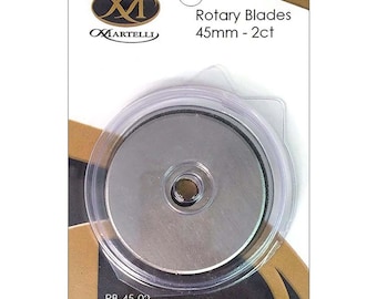 Puede incluir: Un paquete de dos cuchillas rotativas Martelli de 45 mm. Las cuchillas circulares de metal plateado están encerradas en una funda protectora de plástico transparente sobre un soporte de cartón blanco y dorado. El texto dice Rotary Blades 45mm - 2ct y RB-45-02.