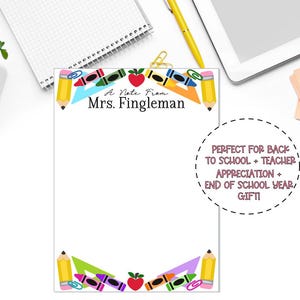 May include: A rectangular notepad featuring a white background with a colorful border of pencils, crayons, paper clips, rulers, and apples. The text at the top reads A Note From Mrs. Fingleman in black font, centered on the page.