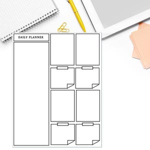 May include: A white daily planner sheet with black outlines featuring a large vertical rectangular section on the left and six smaller rectangular boxes on the right, some with folded corners, all arranged on a clean white background.