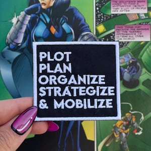 May include: Black iron-on patch with white text that reads "PLOT PLAN ORGANIZE STRATEGIZE & MOBILIZE".