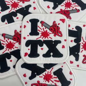 May include: Five white embroidered patches with the text "I ♥ TX" in black with a red chainsaw and blood splatter design.