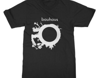 May include: Black t-shirt with a white graphic of a circle with a black center and a white, spiky, abstract design around it. The text "bauhaus" is printed in white above the graphic.