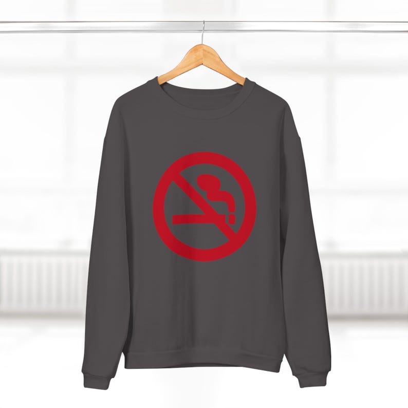 K&ouml;nnte beinhalten: Ein dunkelgrauer Pullover mit einem roten Rauchverbotsschild. Das Schild hat einen diagonalen Strich durch eine Silhouette, die eine Zigarette h&auml;lt.