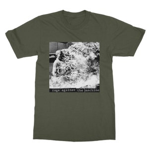 May include: A green t-shirt with a black and white image of a person engulfed in flames. The text "rage against the machine" is printed in black below the image.