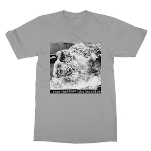 May include: A grey t-shirt with a black and white image of a person engulfed in flames. The text "rage against the machine" is printed below the image.