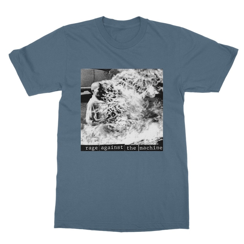 May include: A blue t-shirt with a black and white image of a person engulfed in flames. The text "rage against the machine" is printed below the image.