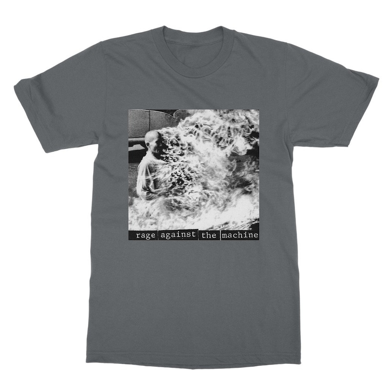 May include: A dark gray t-shirt with a black and white image of a person engulfed in flames. The text "rage against the machine" is printed in white below the image.