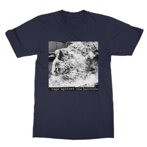 May include: A navy blue t-shirt with a black and white image of a person engulfed in flames. The text "rage against the machine" is printed in white below the image.