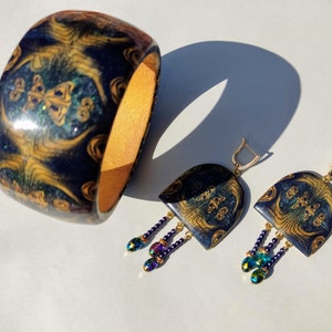 Multi-colored jewelry set, consisting of a wide bracelet and earrings with glass beads.