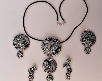 Black/white jewelry set consisting of a pendant and two pairs of earrings.