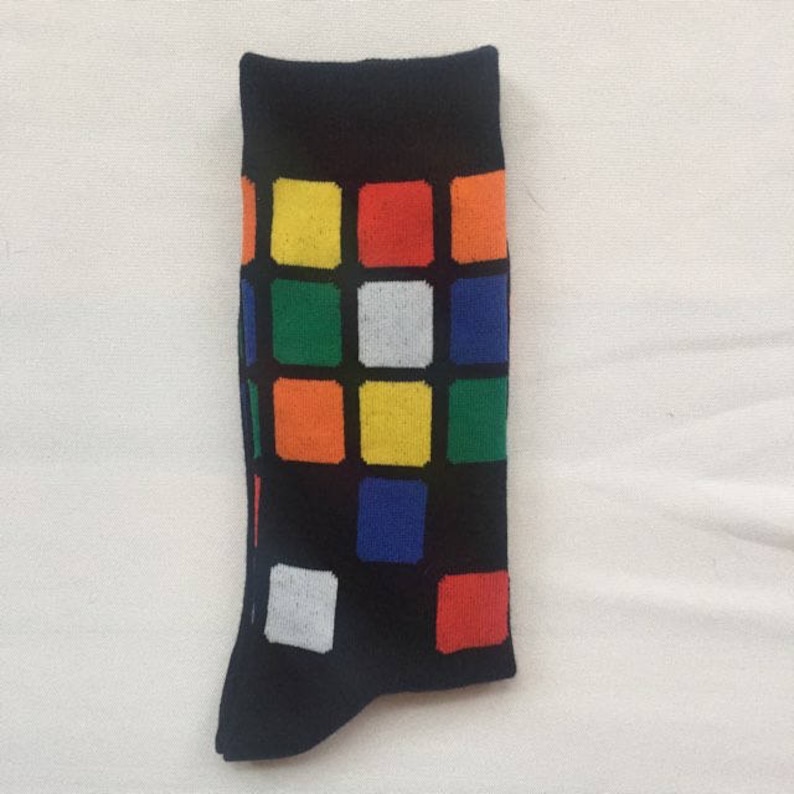 May include: A pair of black socks with a colorful Rubik's Cube pattern. The socks have a white, yellow, orange, green, blue, and red design.