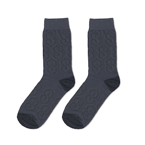 Könnte beinhalten: Ein Paar dunkelgraue Socken mit einem geometrischen Muster. Das Muster besteht aus sich wiederholenden Formen, die dem Buchstaben "S" ähneln.