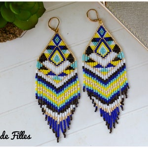 May include: A pair of long, beaded earrings with a geometric pattern in shades of blue, yellow, white, and black. The earrings have a fringe of beads at the bottom.