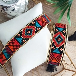 Peut inclure: Deux bracelets en perles avec un motif géométrique dans des tons de rouge, orange, bleu, noir et or. Les bracelets sont sur une surface blanche.