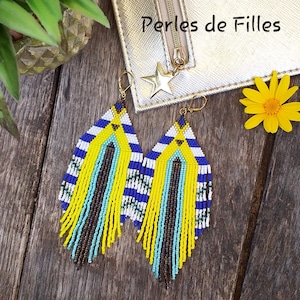 Peut inclure: Une paire de longues boucles d'oreilles en perles avec un motif géométrique dans les tons jaune, bleu, blanc et noir. Les boucles d'oreilles sont faites de petites perles colorées et ont un design en frange.
