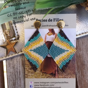 May include: Diamond-shaped beaded earrings with a geometric pattern in black, teal, yellow, and white. The earrings have gold-colored circular studs. The image also shows a business card with the text "Perles de Filles".