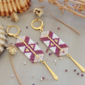 May include: A pair of pink and white beaded earrings with gold hooks and long gold dangles. The earrings have a geometric pattern.