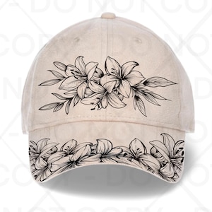 May include: A beige baseball cap featuring a black floral design of lilies. The lilies are arranged across the front and along the brim of the cap. The cap has a curved brim and a fabric strap closure.