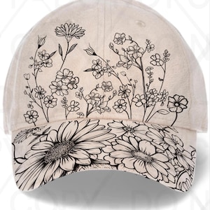 May include: A beige baseball cap featuring a black floral design. The cap's crown is adorned with various flowers and stems, while the brim showcases large daisies. The cap has a curved brim and a button on top.