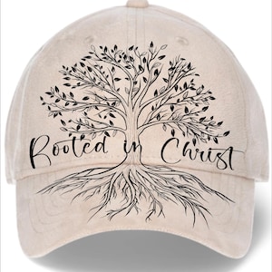 May include: A beige baseball cap featuring a black tree design with the words "Rooted in Christ." The tree illustration includes branches, leaves, and roots. The cap has a curved brim and an adjustable strap.