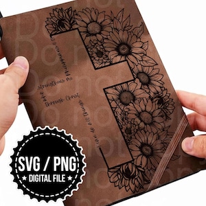 May include: A brown leather-like journal cover featuring a large cross outline filled with detailed black line art of sunflowers. The text "I can do all things through Christ who strengthens me Philippians 4:13" is printed vertically along the cross.